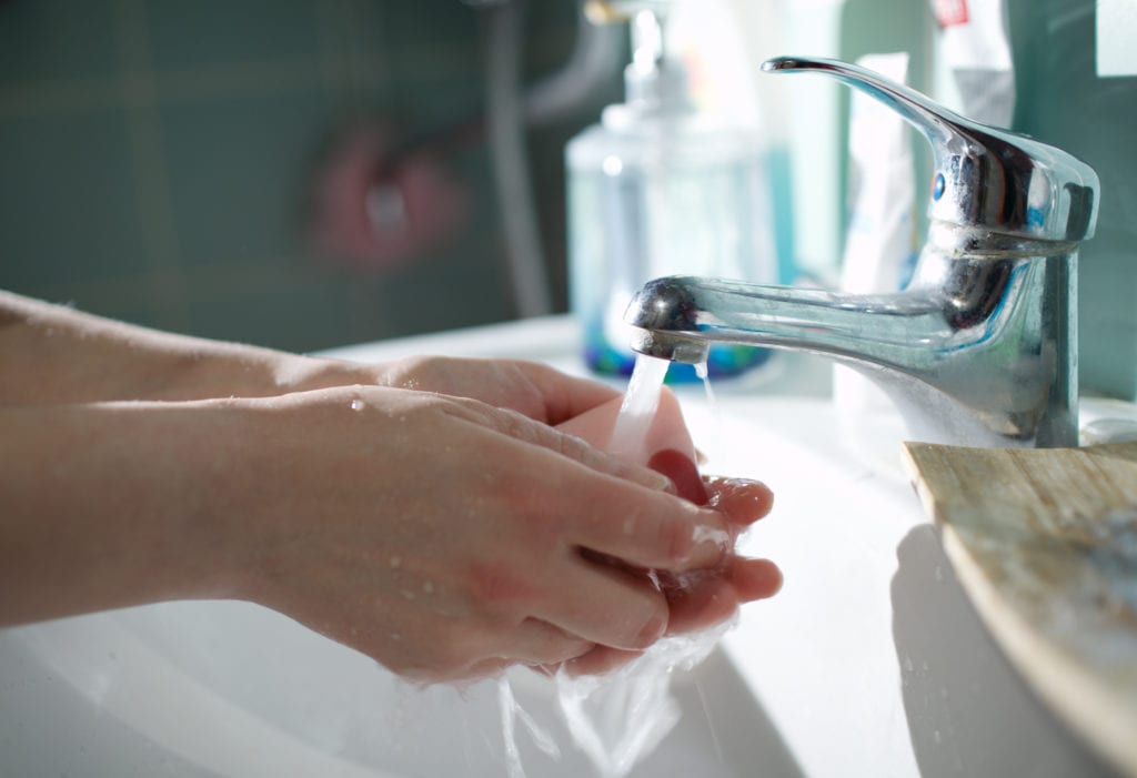 person washing hands in sink