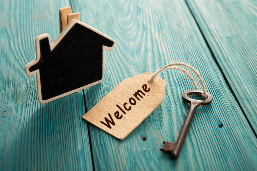 House shaped decoration next to key with tag reading "Welcome"