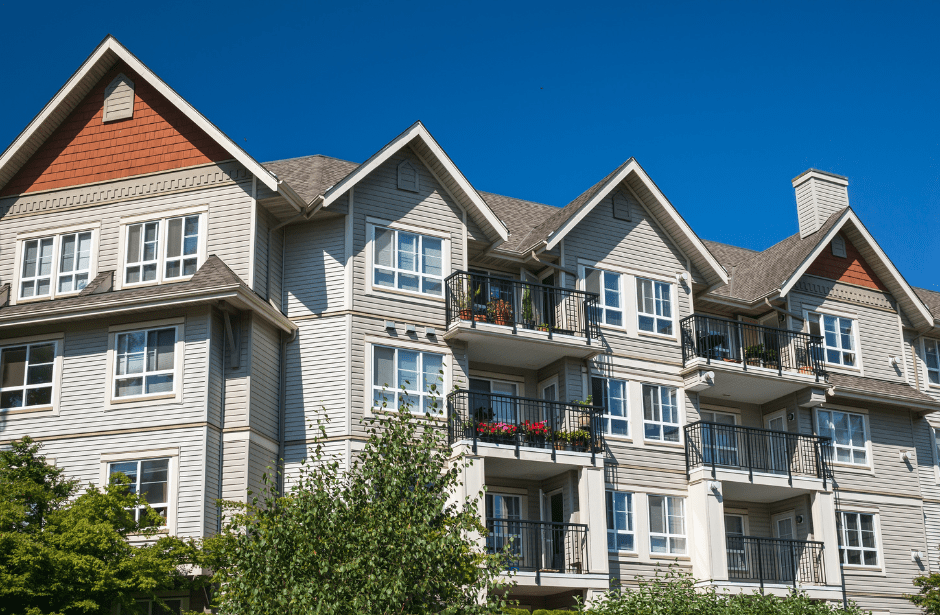 Exterior of large apartment complex with tan siding and balconies. 