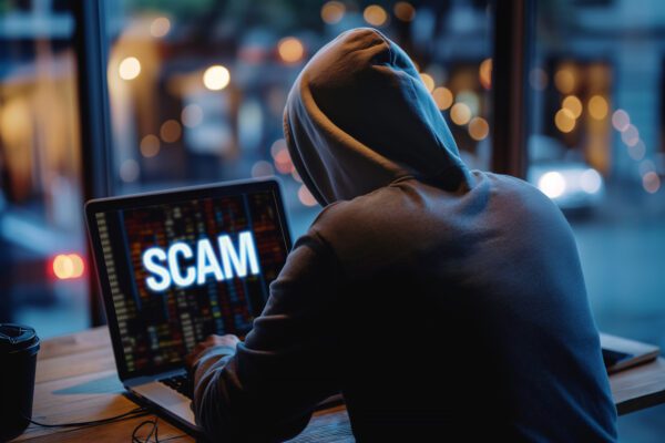 Hooded individual committing online fraud