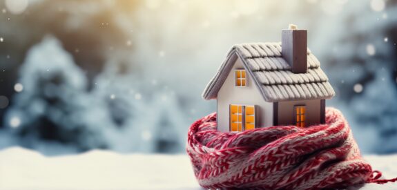 Miniature house wrapped in a scarf in a snowy setting